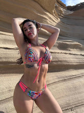 Laden Sie das Bild in den Galerie-Viewer, Deira hand-beaded ruched bikini in coral and gold, showcasing vibrant colors against a natural backdrop.