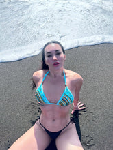 Charger l'image dans la galerie, Woman in turquoise hand-beaded bikini sitting on beach, showcasing elegant design and craftsmanship.