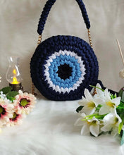 Load image into Gallery viewer, Cute Handmade Greek Eye crochet Handbag displayed with flowers and soft lighting, showcasing its intricate crochet design.