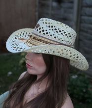 Load image into Gallery viewer, Close-up of a woman wearing a handmade Iraca palm hat with intricate embroidery and decorative bands.