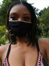 Load image into Gallery viewer, Model wearing Adara hand-beaded face mask with colorful trim in a lush outdoor setting.