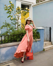 Load image into Gallery viewer, Model wearing a pink dress and straw hat, holding a burnt orange leather handbag with Mola design outside a colorful building.