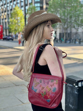 Load image into Gallery viewer, Stylish young woman with a handmade Tala leather handbag and a straw hat in an urban setting.