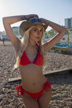 Load image into Gallery viewer, Model wearing a red macrame bikini and a wide-brimmed hat on a beach, showcasing elegant craftsmanship.