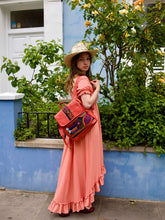 Load image into Gallery viewer, Woman in a pink dress wearing a handcrafted tangerine leather rucksack with traditional Mola applique.
