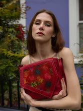 Load image into Gallery viewer, Handmade Tala Leather Handbag held by a model, showcasing vibrant hand-painted art on a red leather crossbody bag.