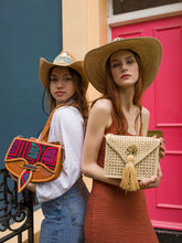 Load image into Gallery viewer, Two women showcasing vibrant artisanal bags in stylish outfits against a colorful backdrop.