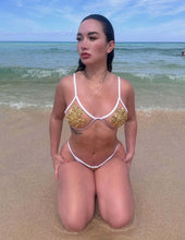 Cargar imagen en el visor de la galería, Model showcasing the Nina Hand Beaded Bikini on the beach, featuring gold beads and a stylish silhouette.