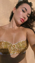 Cargar imagen en el visor de la galería, Nina hand beaded bikini in white with gold accents, showcased on a model in a sandy environment.