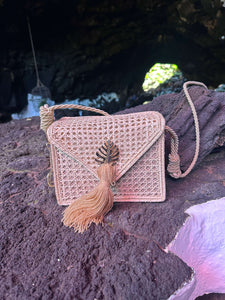 Handwoven Iraca palm leaf shoulder bag with decorative tassel, showcasing artisanal craftsmanship and chic design.
