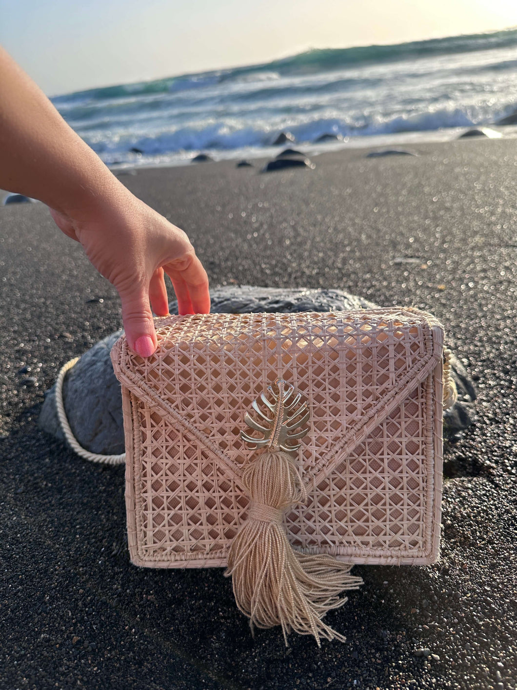 Handwoven Iraca Palm Leaf Shoulder Bag resting on the beach, showcasing its intricate craftsmanship and elegance.